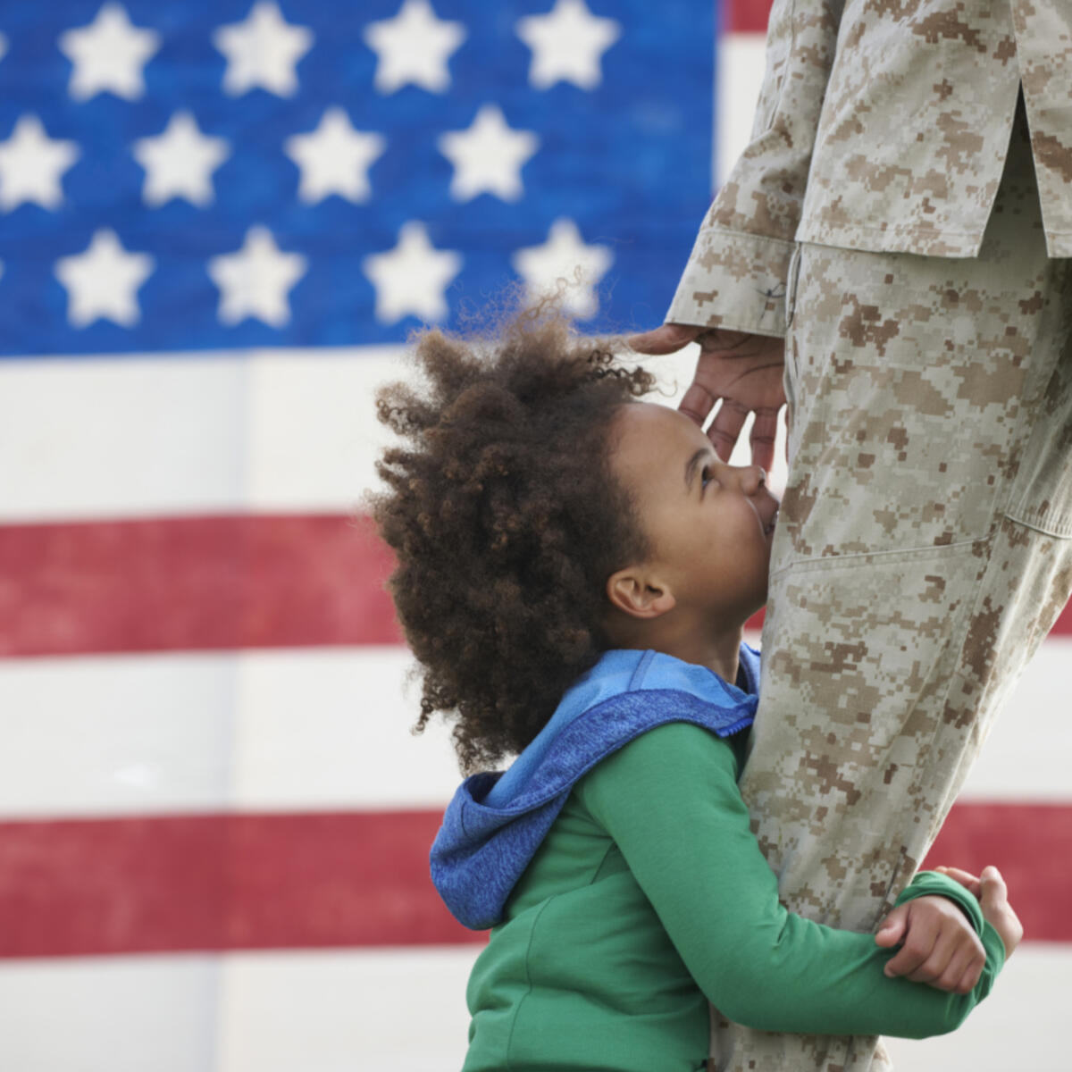 A child hugs a service member in uniform.