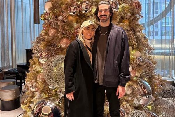 Delta customers Paige and Ian, who met in a Delta Sky Club, pose in front of a Christmas tree.