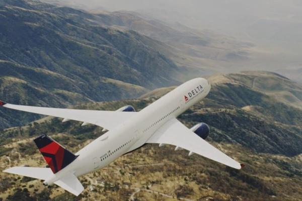 An A350 Delta aircraft flies over mountains