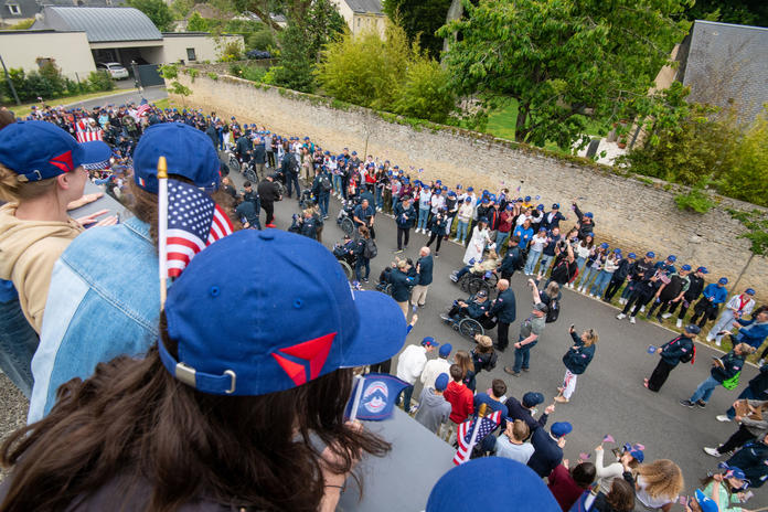 Os alunos de Bayeux dão as boas-vindas aos veteranos com um desfile para a tão esperada visita à escola.