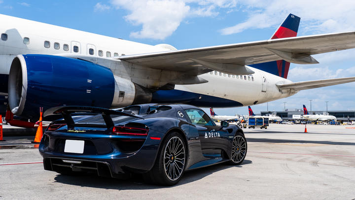 A Porsche 918 Spyder waits on the ramp to escort a Delta customer to a connecting flight. 