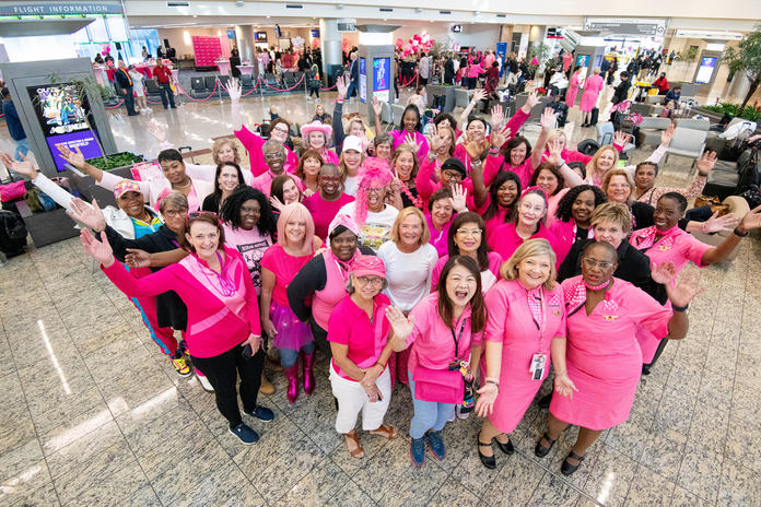 A group of breast cancer survivors pose for a group photo before boarding Delta's Breast Cancer One charter flight.