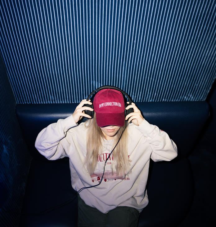 A SkyMiles member enjoys the Delta Sync Space at Delta's SXSW lounge while wearing exclusive Delta x SXSW merch. 
