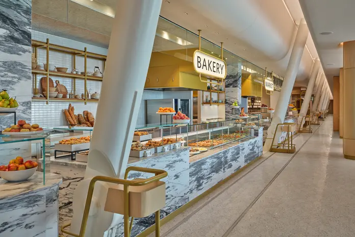 Fan-shaped marble mosaic tiles in the Market dining area at The Delta Lounge-JFK pay tribute to famed New York brasseries. The penny-round ceiling over the food counter is a hat-tip to the original JFK terminal, designed by famed architect Eero Saarinen.