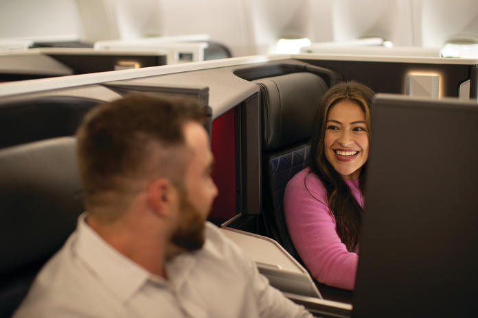 Customers sitting in Delta One smile at each other
