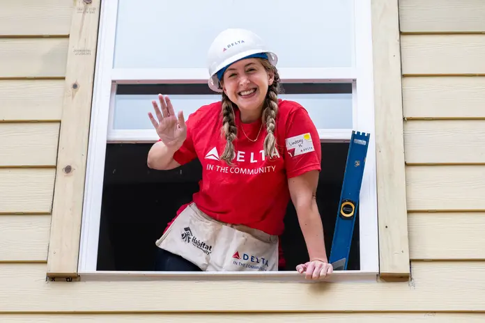 Delta Atlanta Habitat for Humanity volunteer standing in window, waving and smiling