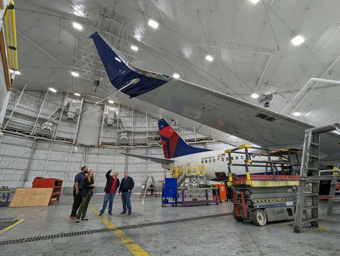 Group of people looking up at airplane winglet.