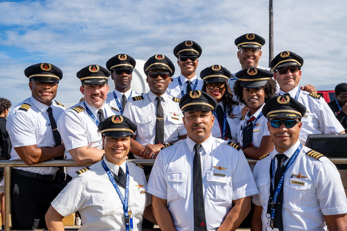 Group of Delta pilots in uniform posing outdoors.