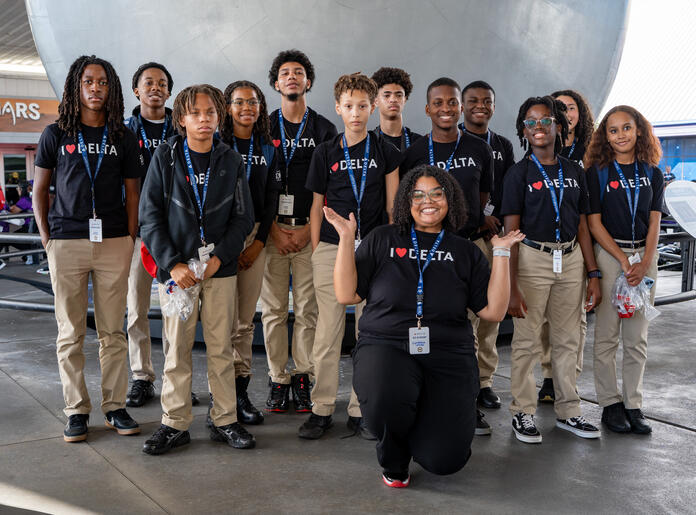 DREAM flight participants posing for in front of a large metallic structure wearing matching black Delta t-shirts.