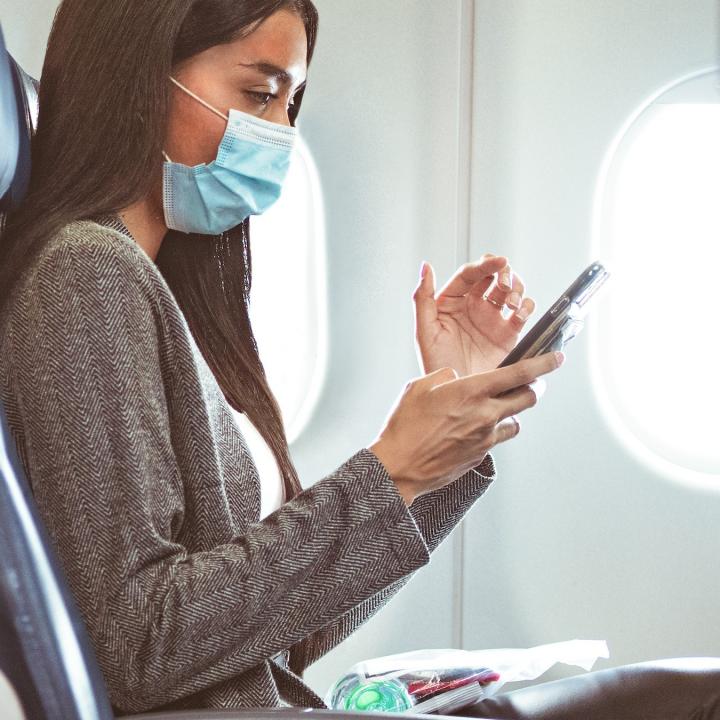 Delta customer in mask at seat with phone