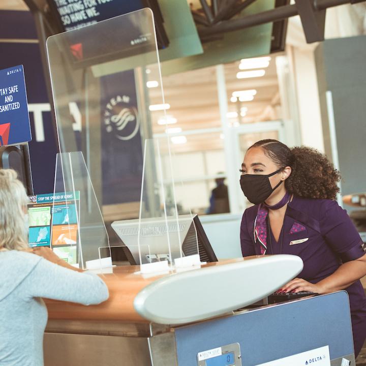 Delta employee and customer at ticket counter with mask
