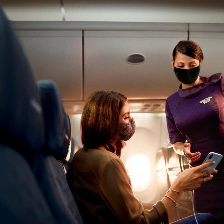 A Flight Attendant assists a passenger on a flight.