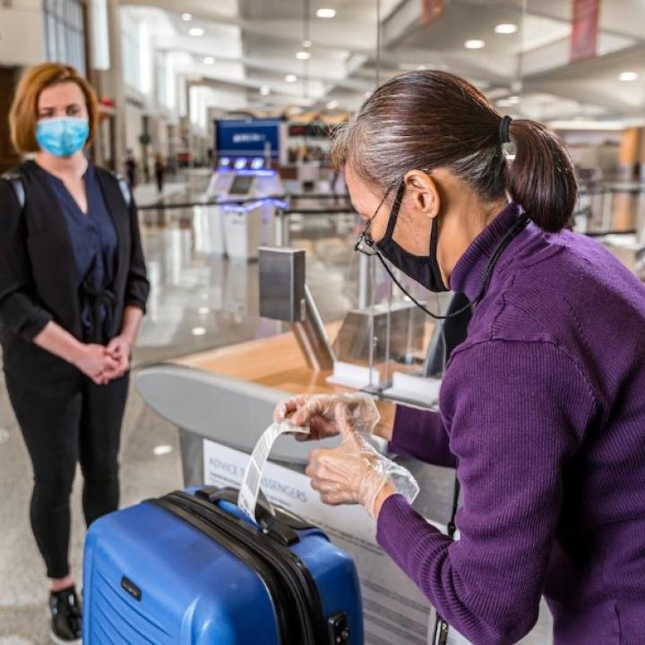 A gate agent helps a passenger check a bag.