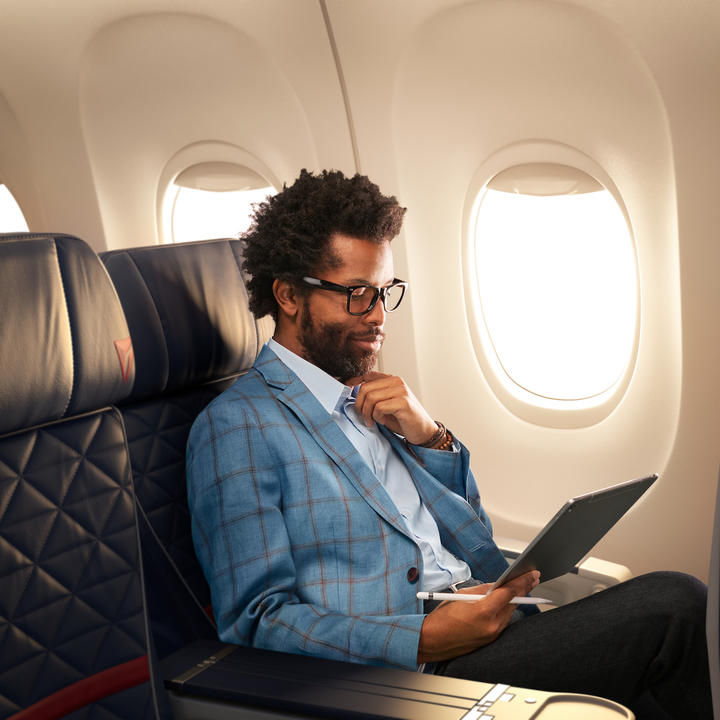 A man works on a tablet while seated in Delta domestic first class.