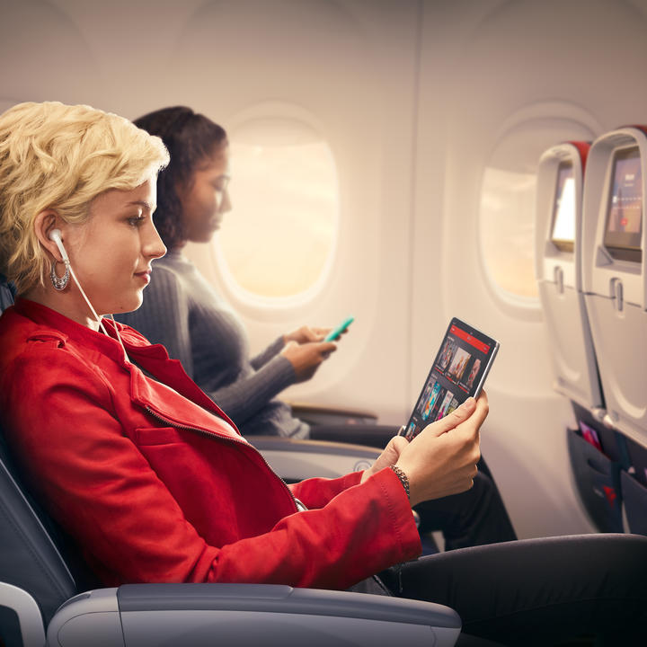Customers use mobile devices while seated in Delta Comfort+.