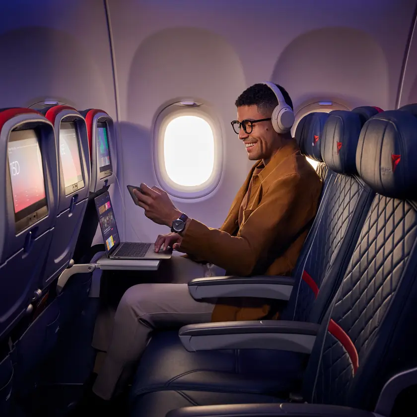 A customer uses Delta's fast, free Wi-Fi on board on their smart phone and laptop.