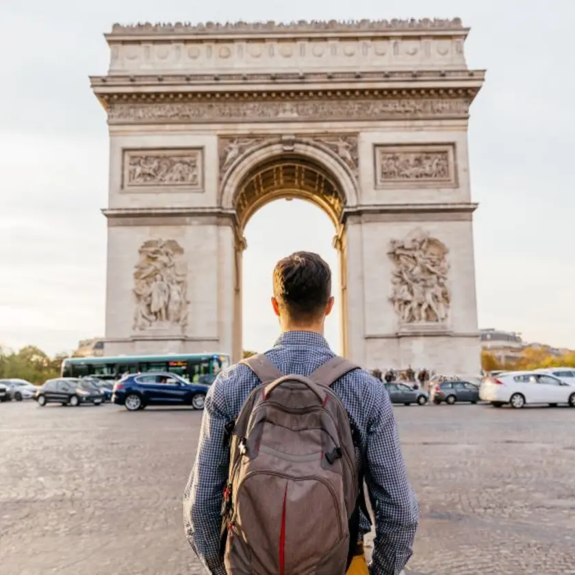 A traveler stands in front of the Arc de Triomphe in Paris, France.