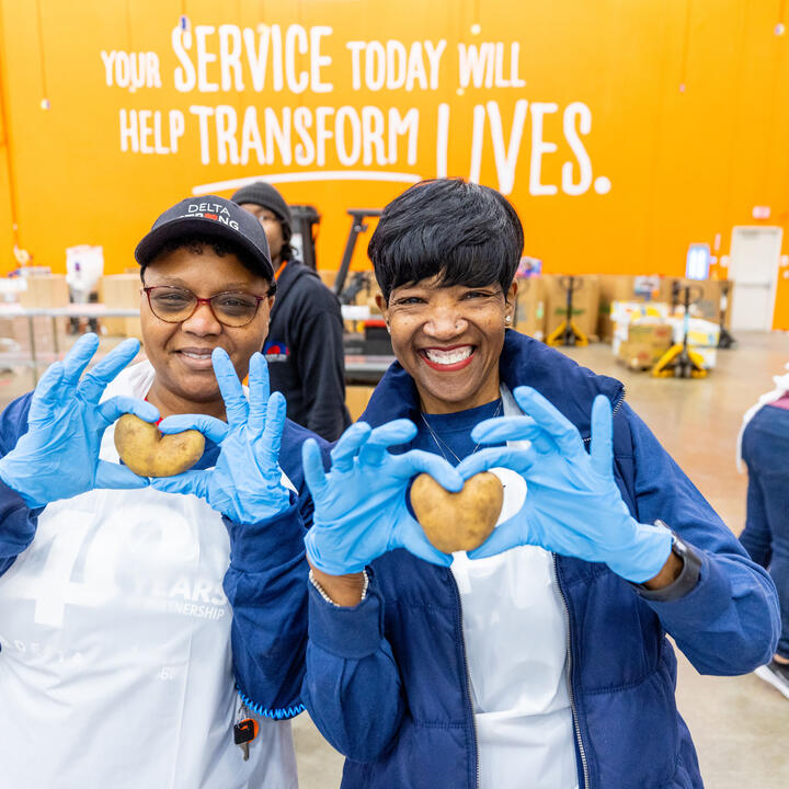 Delta employee volunteers holding heart-shaped potatoes