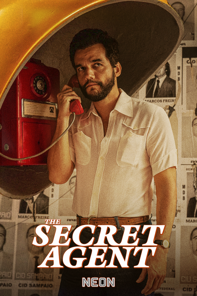 A person in a light short‑sleeve shirt stands inside a yellow public phone booth using a red telephone, with walls covered in black‑and‑white posters and the title ‘The Secret Agent’ below.
