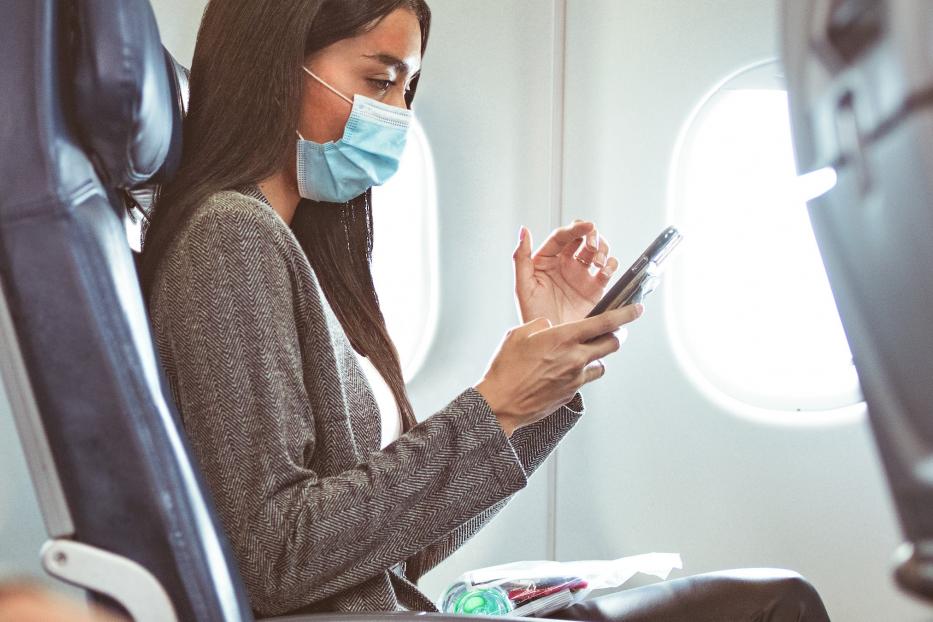 Delta customer in mask at seat with phone