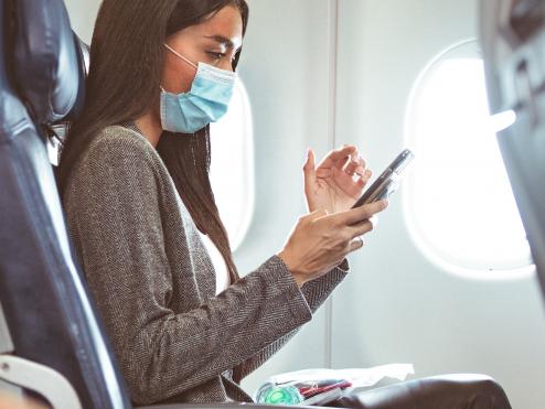 Delta customer in mask at seat with phone