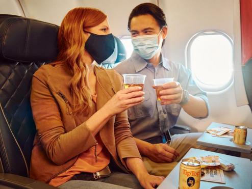 Delta customers with drinks and masks in flight