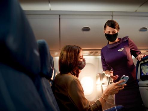 A Flight Attendant assists a passenger on a flight.