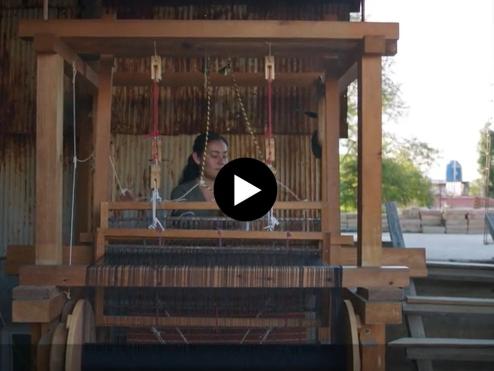 A woman works at a loom.