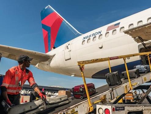 A Delta employee loads baggage onto a plane.