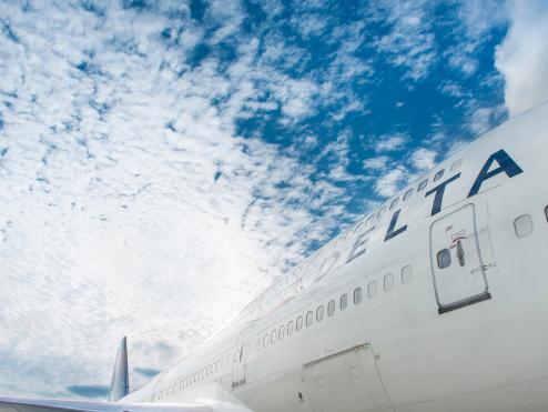 Close up of Delta aircraft with blue skies and clouds