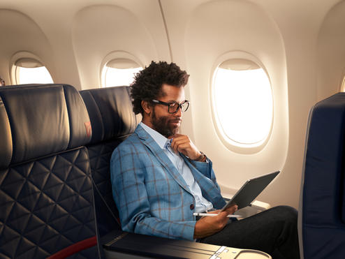 A man works on a tablet while seated in Delta domestic first class.