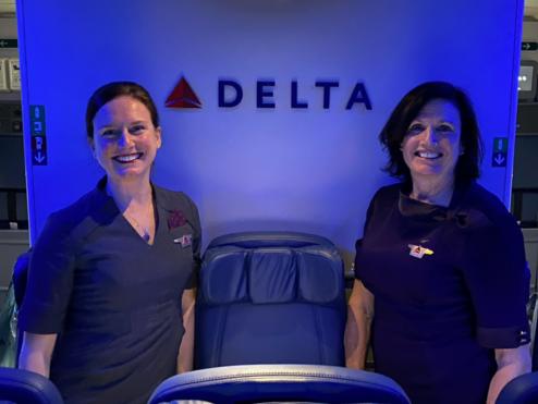 A mother and daughter duo who have nearly 30 years of combined service at Delta pose for a photo onboard a plane.