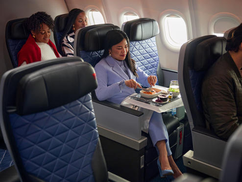 A Delta customer seated in Delta Premium Select enjoys a meal.