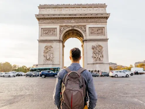 A traveler stands in front of the Arc de Triomphe in Paris, France.