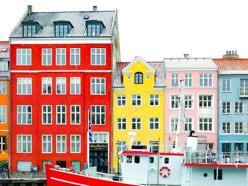 Nyhavn district with boats on water canal and colorful row of old houses in Copenhagen, Denmark