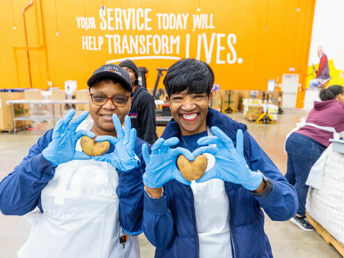 Delta employee volunteers holding heart-shaped potatoes