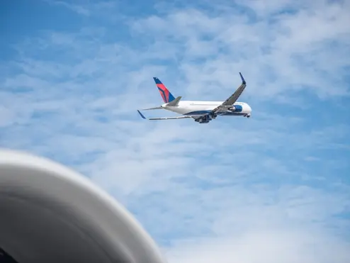 Delta 767 aircraft shortly after takeoff with blue sky and clouds in background