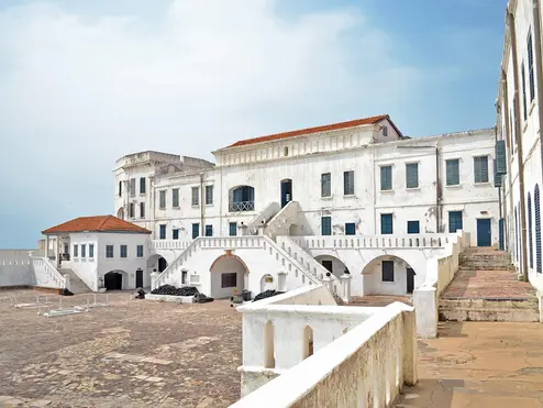 Ghana's Elmina Castle beneath a blue, lightly cloudy sky.