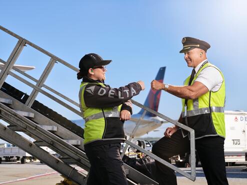 Delta pilot and ground agent giving fist bump on the ramp