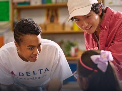 Delta employee volunteer smiling while interacting with a young girl.