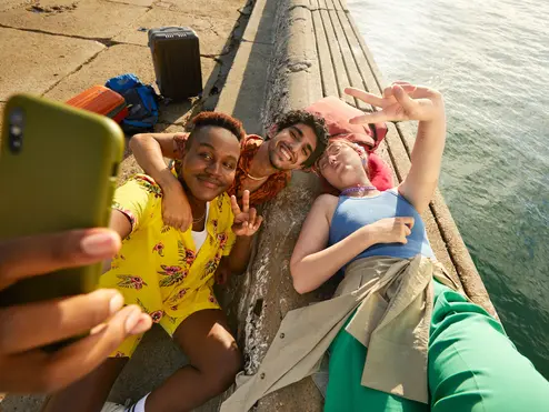 Three people take a selfie next to a body of water