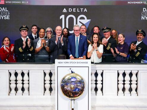 Ed standing in front of the NYSE bell with a group of employees, all clapping