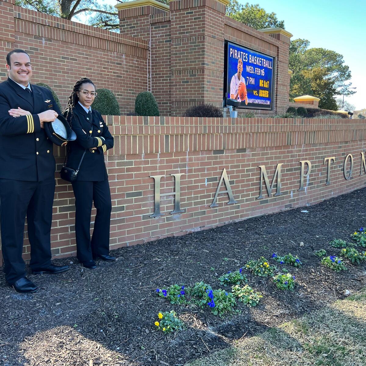 Two aviators stand outside of Hampton University.