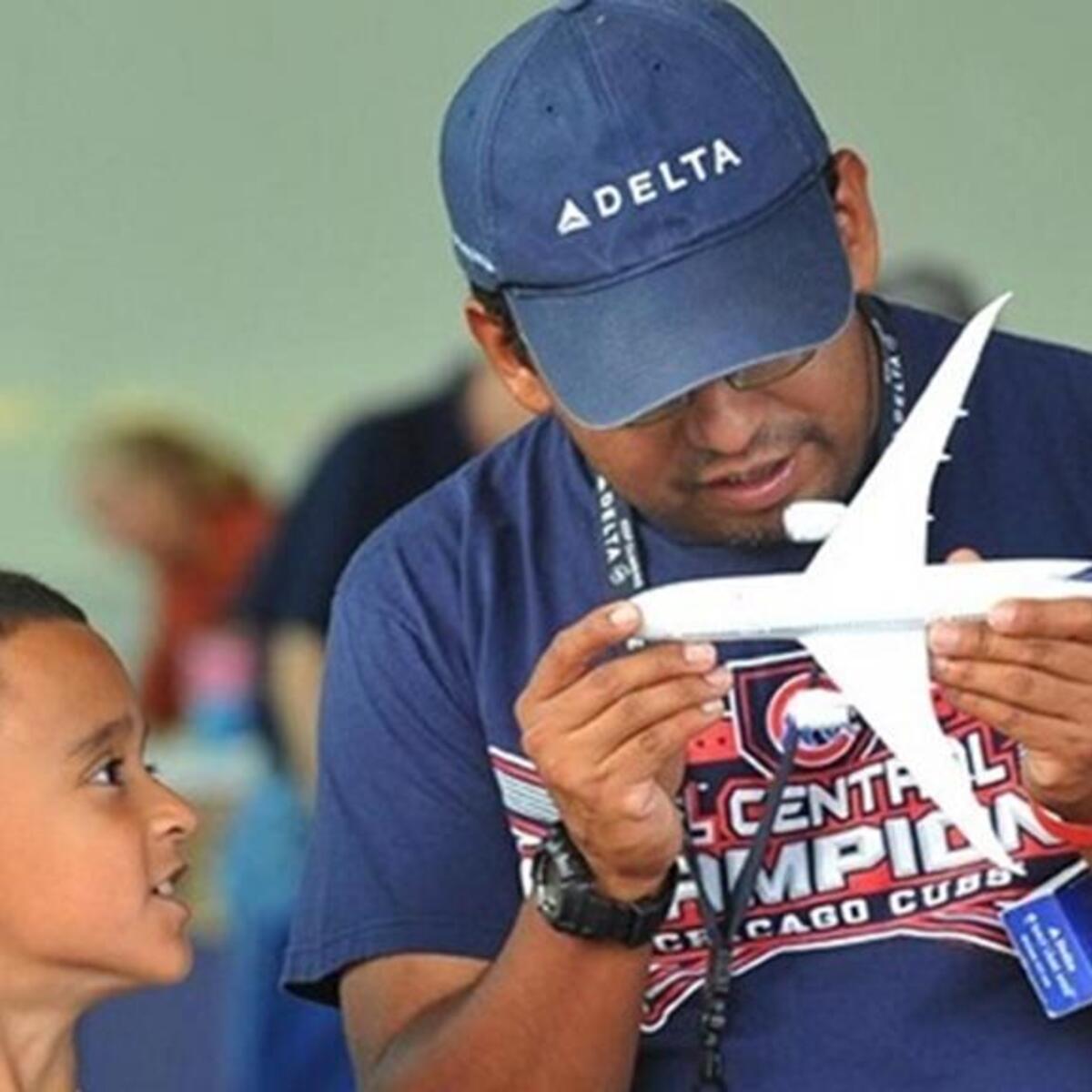 Man holds model airplane while boy looks on.