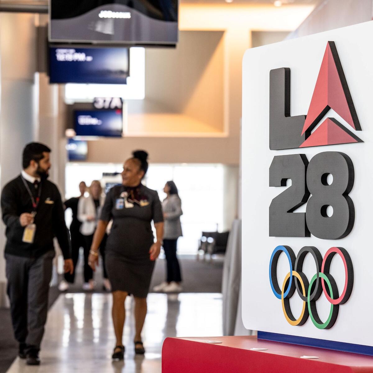 Delta employees walk through LAX near Delta's cocreated logo for LA28 on Sept. 29, 2022.