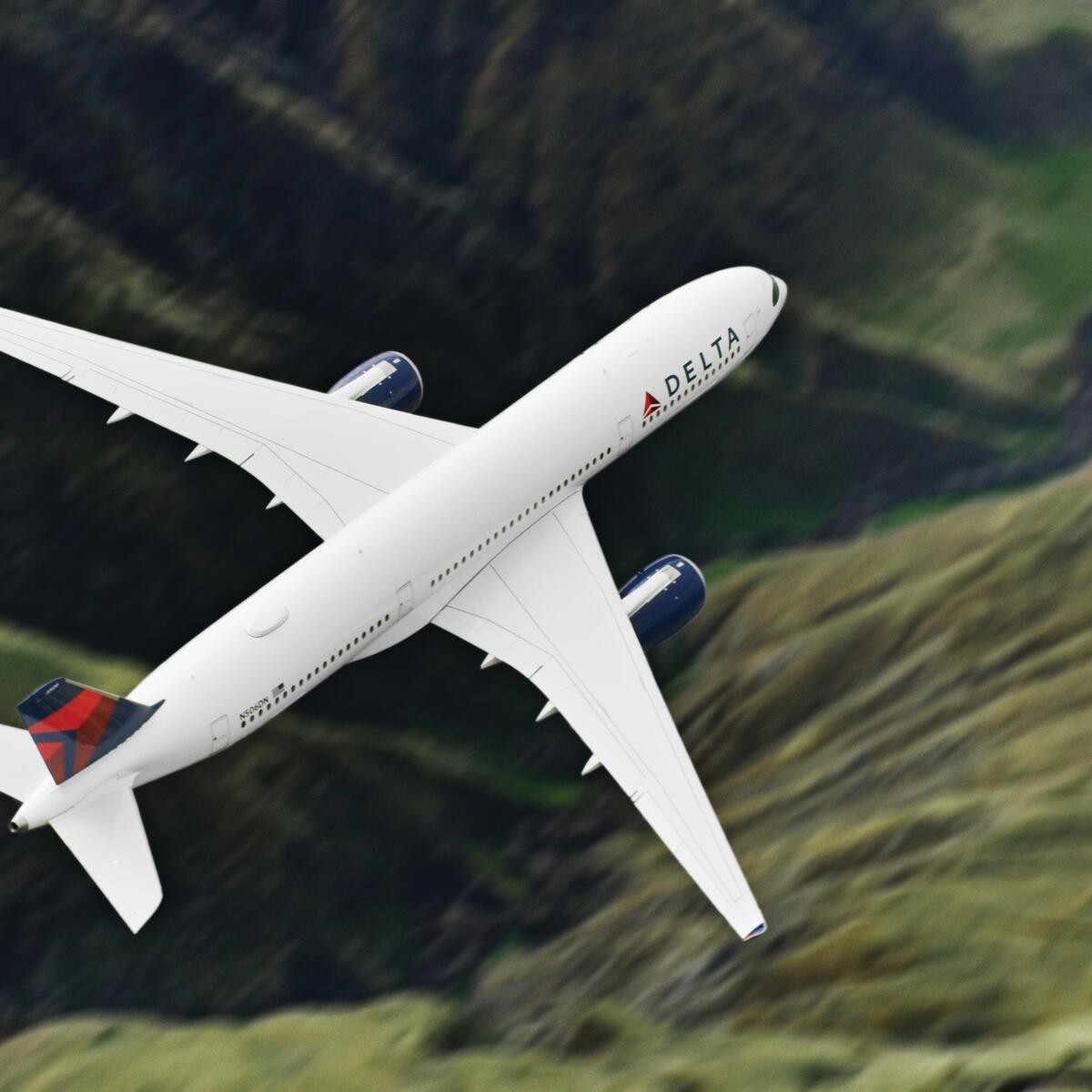 Airbus A359-900 flies over green mountains