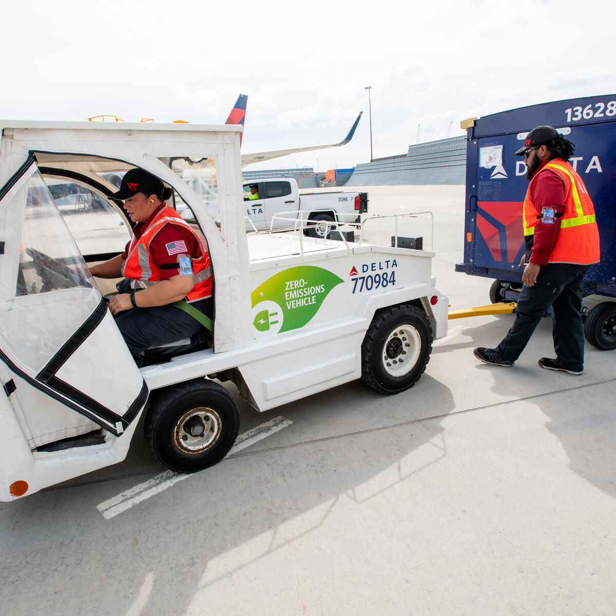 Delta Ramp Agent Sinai Pauni (left) and Aircraft Load Agent Thomas Tuikolovatu (right) operate an electric bag tractor at Salt Lake City International Airport (SLC).