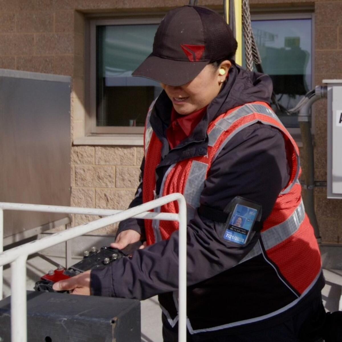 Delta Ramp Agent Sinai Pauni (left) plugs in an electric bag tractor for charging at Salt Lake City International Airport (SLC).