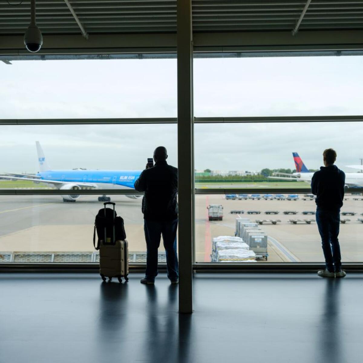 Customers at Schiphol Airport in Amsterdam with Delta and KLM aircraft in the background.