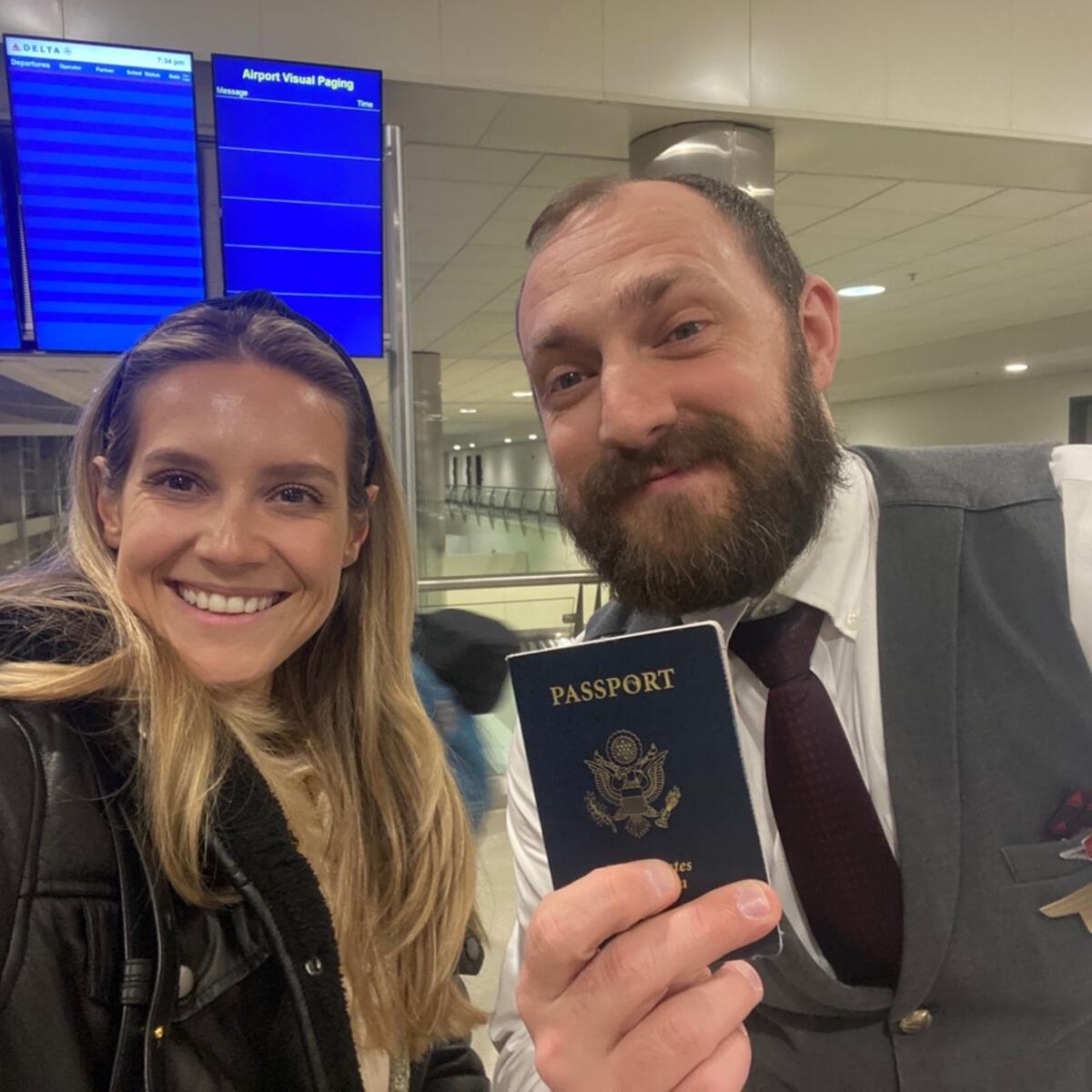Lawryn Fellwock poses with Delta flight attendant Dusty Dills -- holding the passport she left behind on her honeymoon trip.